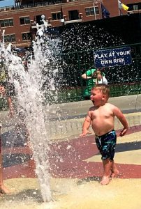 Small boy in a fountain spray of water. 